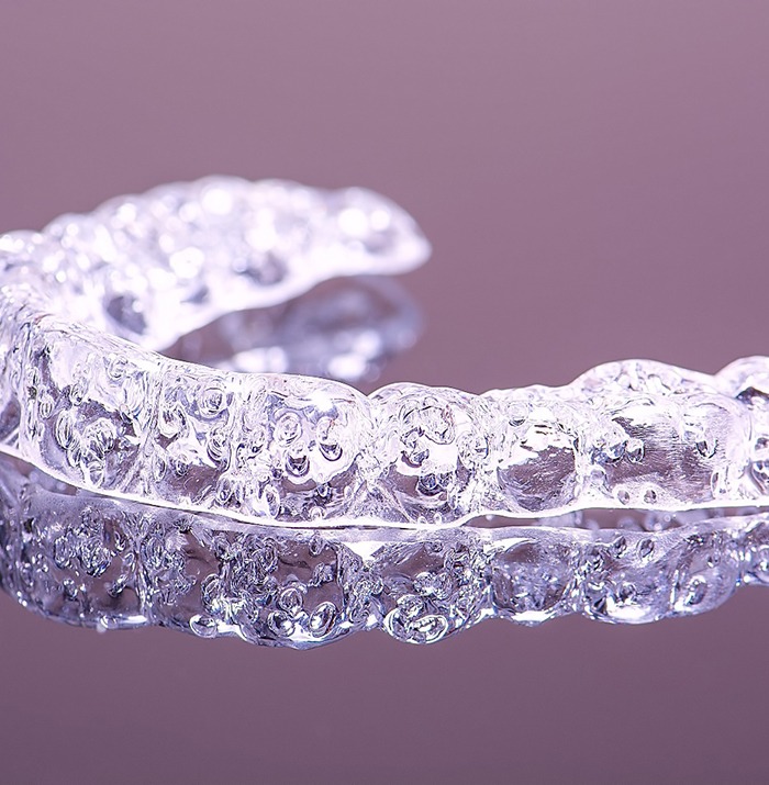 Clear orthodontic aligner on purple background. 