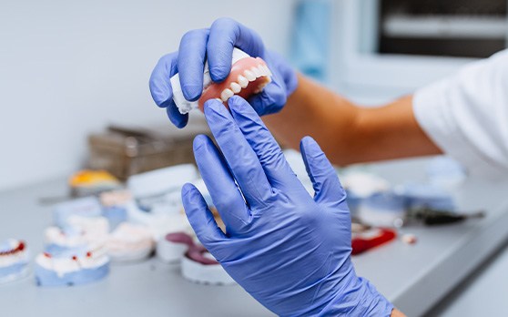 Gloved hands holding a denture