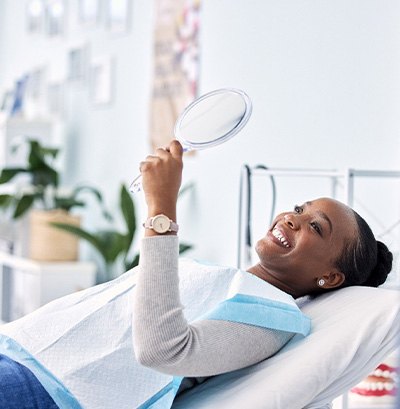 Woman smiling at reflection in handheld mirror