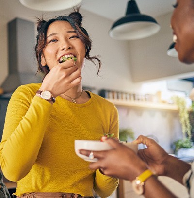 Friends smiling while eating together in kitchen