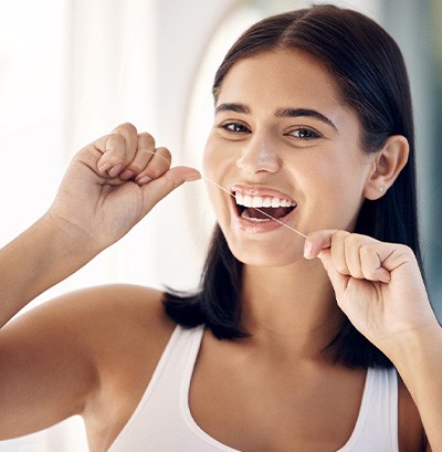 Woman smiling while flossing her teeth