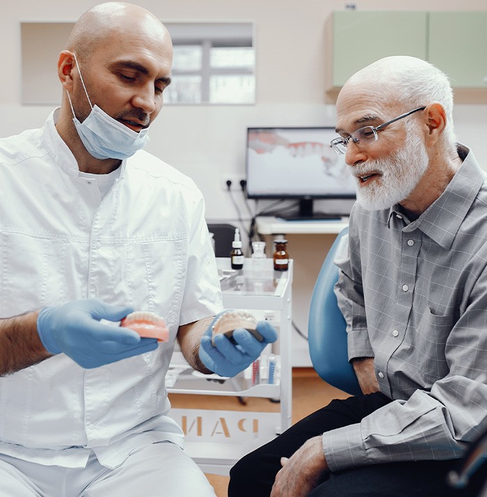 A dentist showing dentures to an older man