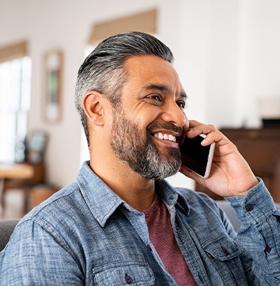 Man smiling while talking on phone at home