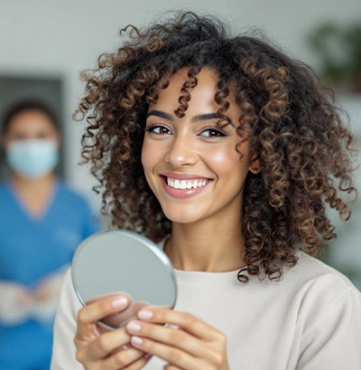 Woman smiling while holding small mirror