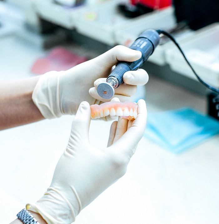 A dental technician further refining a denture