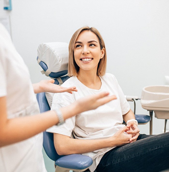 Smiling woman at Invisalign aftercare appointment with dentist