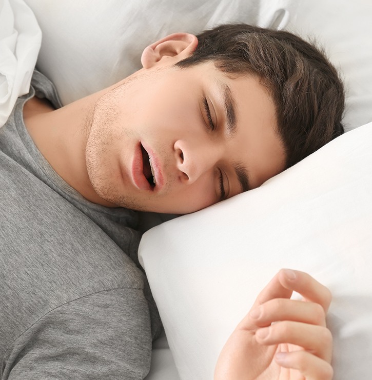 Man in grey shirt snoring in bed