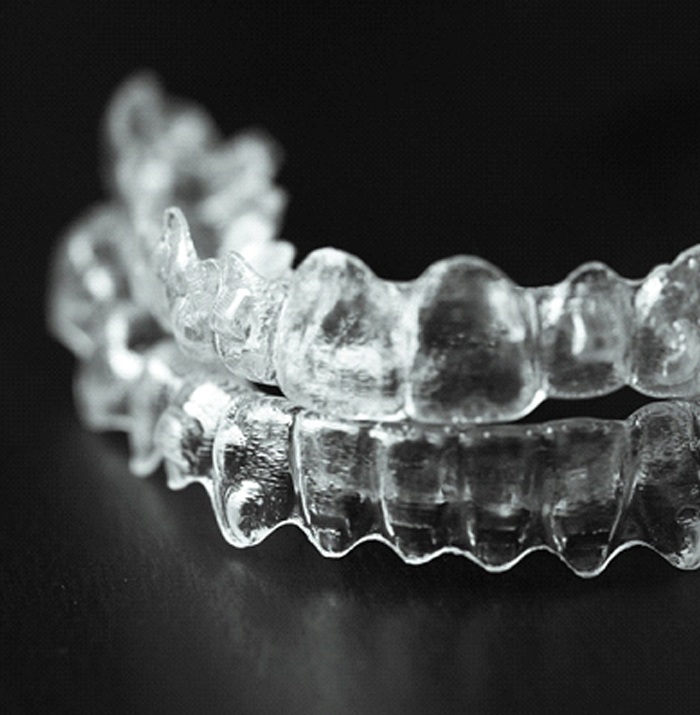 Clear upper and lower Invisalign aligners sitting on a black table