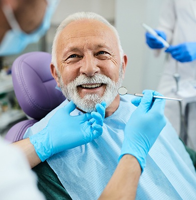 Man with white hair and beard about to undergo dental exam. 