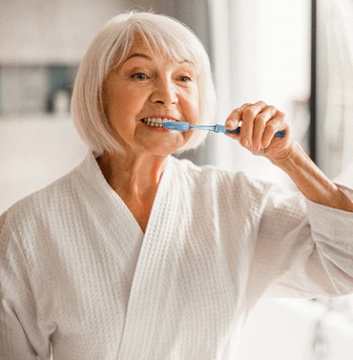 woman brushing teeth in bathroom mirror