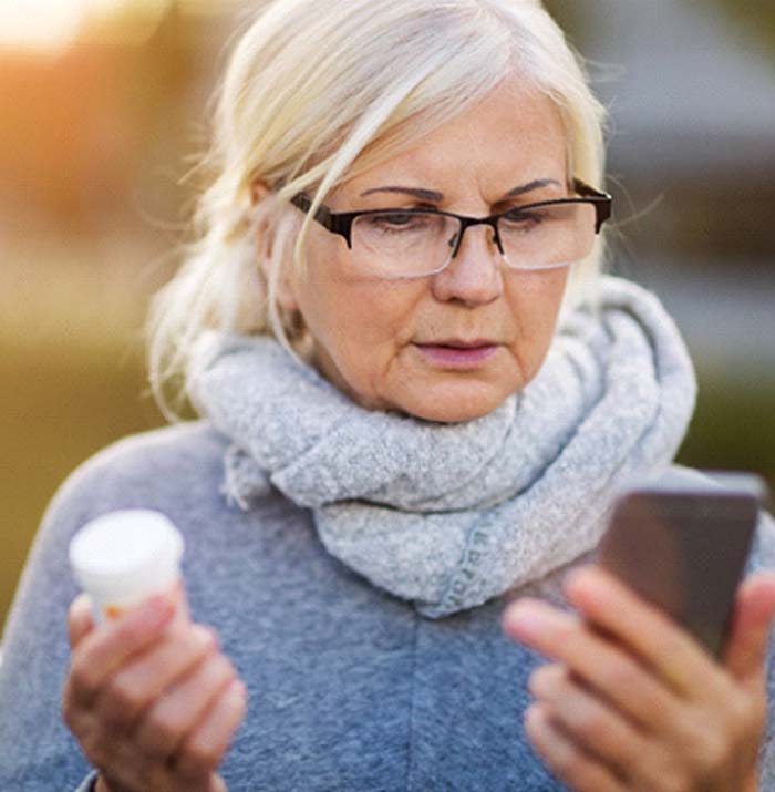 Woman holding medication and mobile phone