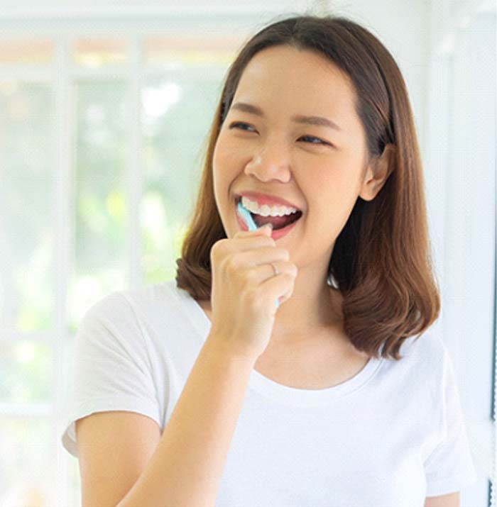 Woman brushing her dental implants in Kansas City