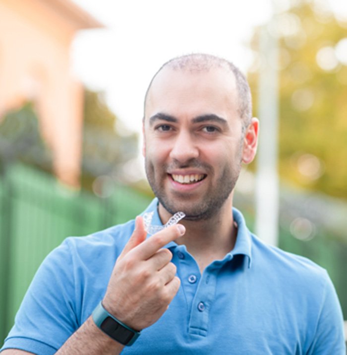 Woman holding a clear aligner for Invisalign.