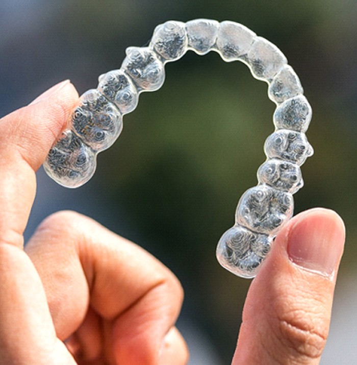 Hand holding up Invisalign aligner