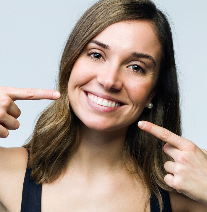 Woman pointing to an attractive smile after Invisalign. 