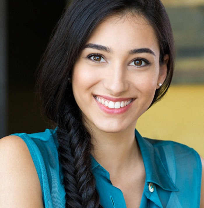 A young woman wearing a sleeveless shirt and her hair braided while showing off her smile makeover in Kansas City