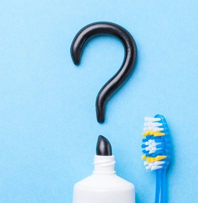 Activated charcoal toothpaste drawing a question mark on a blue background
