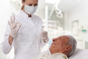 Dental hygienist talking to senior patient in dental chair