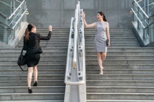 two business people walking past each other and waving