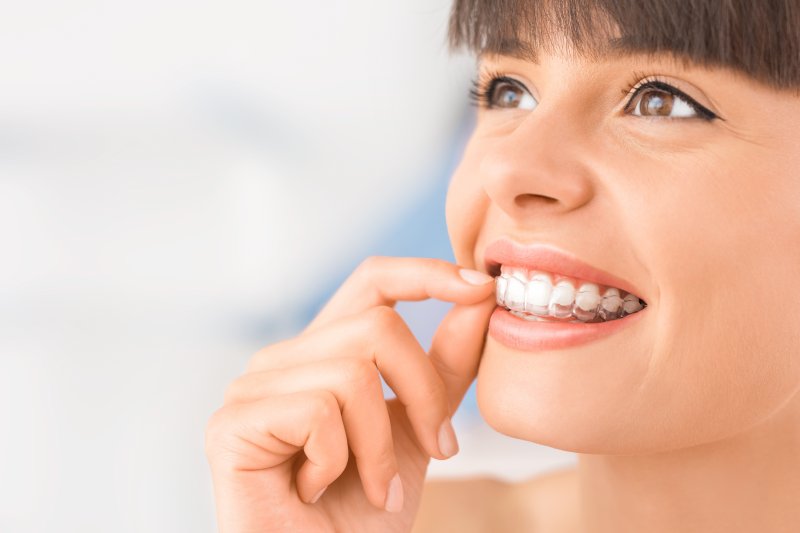 a young woman removes her Invisalign aligner during treatment