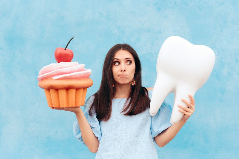 Woman holding giant cupcake and tooth