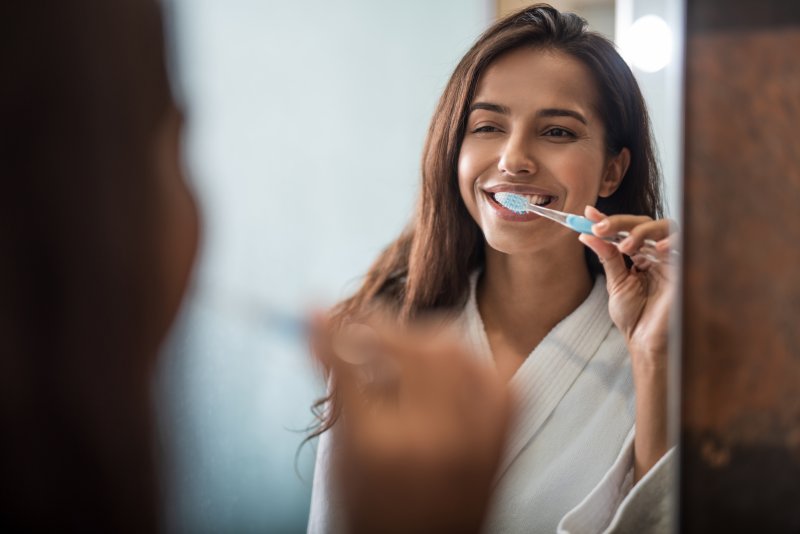 Woman brushing her teeth in front of mirror