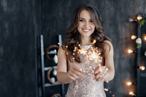 Woman in shiny dress holding up New Year’s sparklers