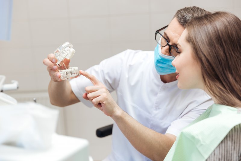 dentist showing a patient a model of dental implants