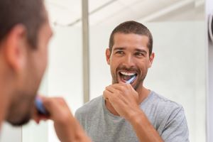 person brushing their teeth in the mirror