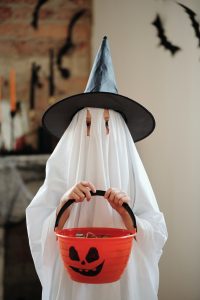 Child wearing a ghost costume holding a candy bucket