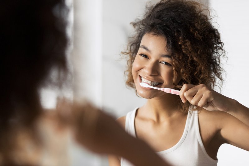 A woman using her toothbrush as she thinks about toothbrush storage