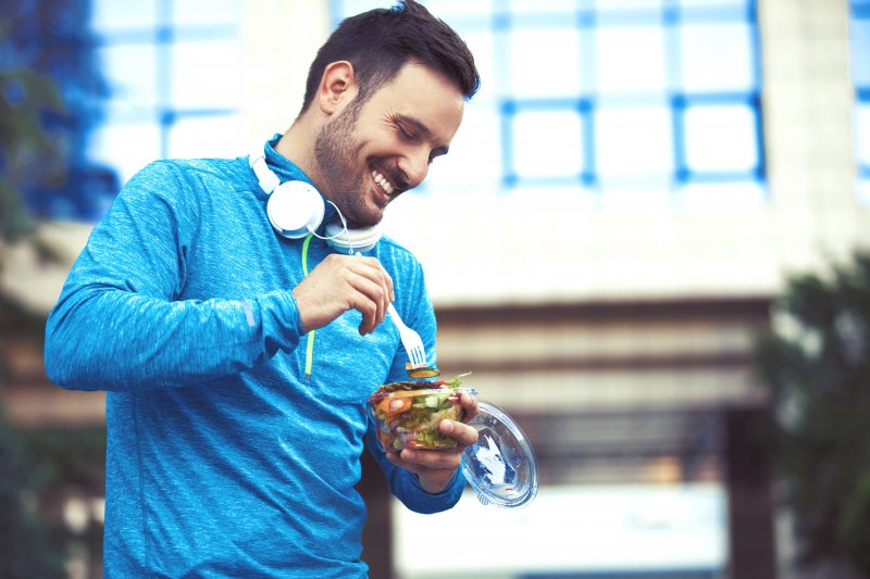 A man smiling as he eats after a workout