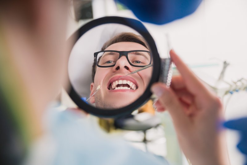 Patient smiling in mirror with new tooth-colored fillings
